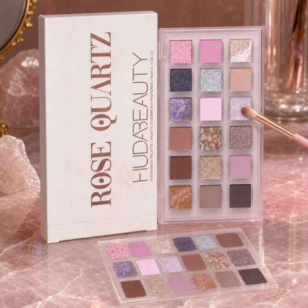 پالت سایه هدی بیوتی Rose Quartz کنار براش و نمونه رنگ روی سنگ رز کوارتز